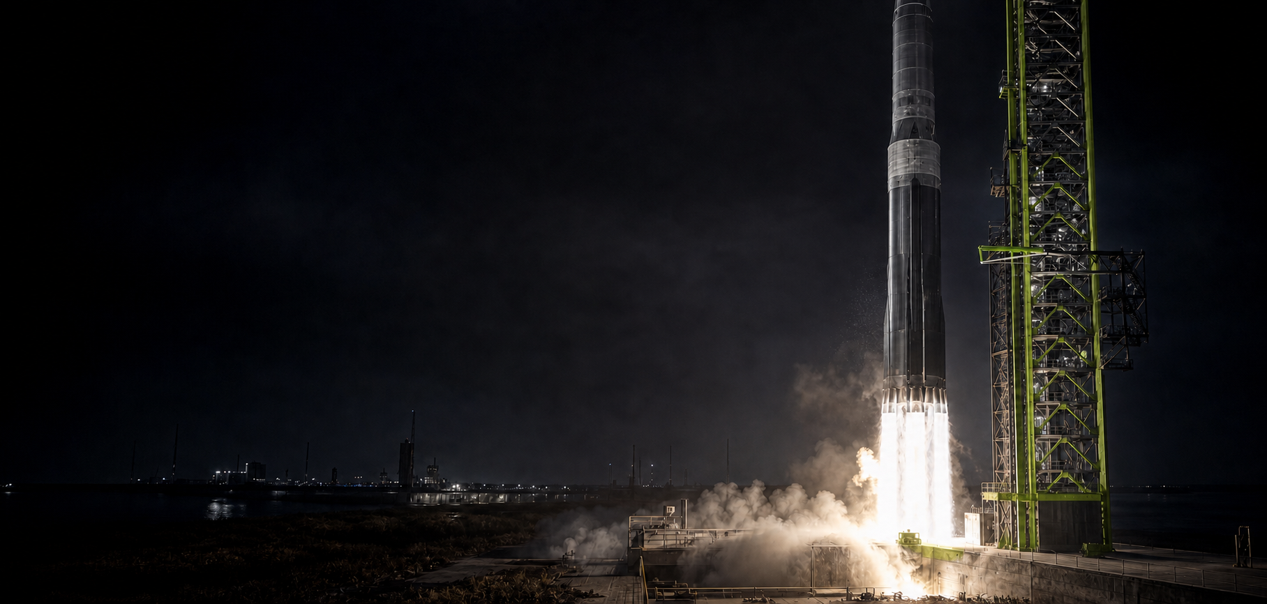 A heavy orbital launch vehicle lifting from a dark coastal launch complex beside an OptiFI-green support tower